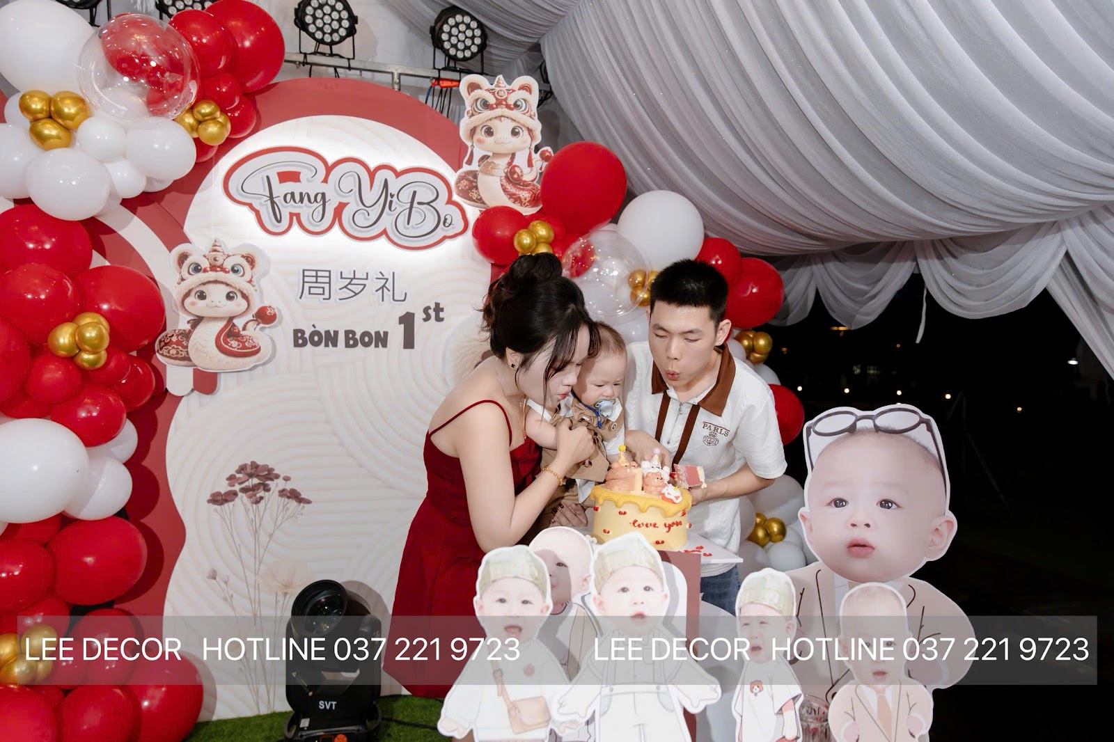 Tiệc thôi nôi 周岁礼 theo phong tục người Hoa tại Bình Dương — backdrop tông đỏ vàng, cổng bóng và bàn bánh do Lee Decor 247 thiết kế và thi công