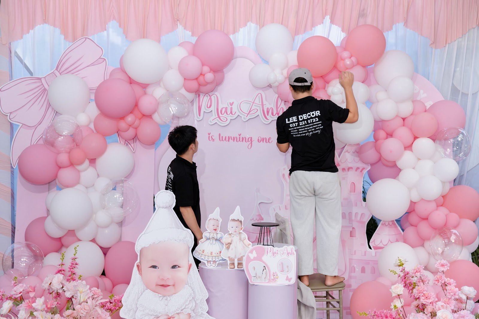 Backdrop thôi nôi bé gái concept công chúa tông hồng pastel với cụm bóng bay và nơ lớn do Lee Decor 247 thi công tại Bình Dương